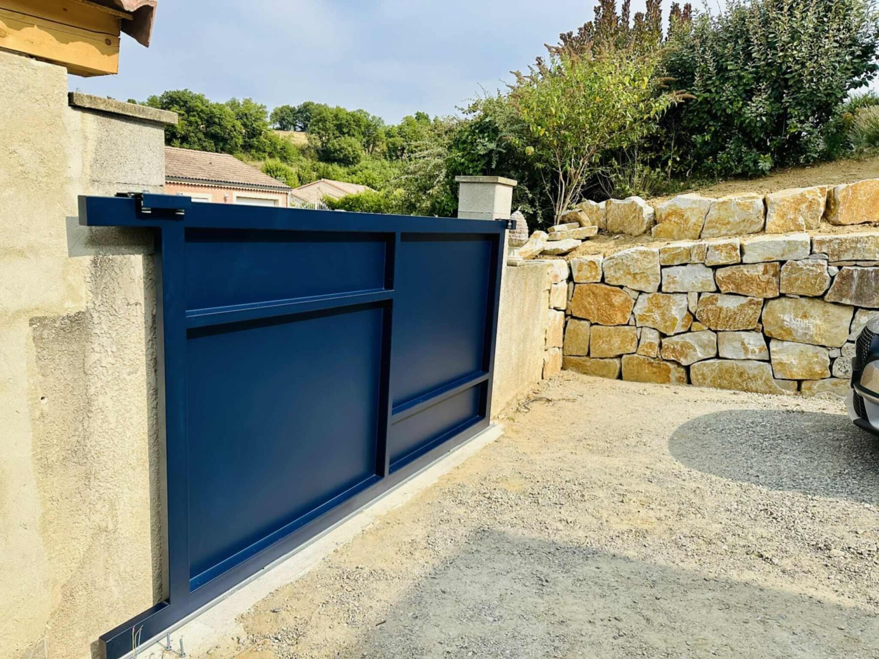 Portail coulissant bleu nuit sur mesure, vue de profil avec rail au sol