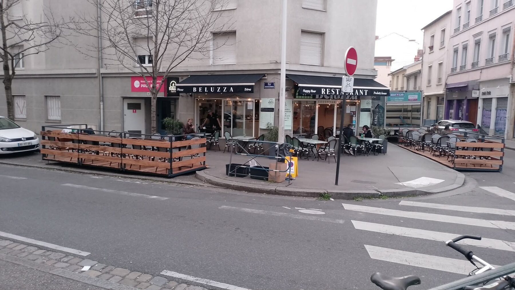 Terrasses commerciales métalliques installées de part et d'autre d'un restaurant à l'angle d'une rue